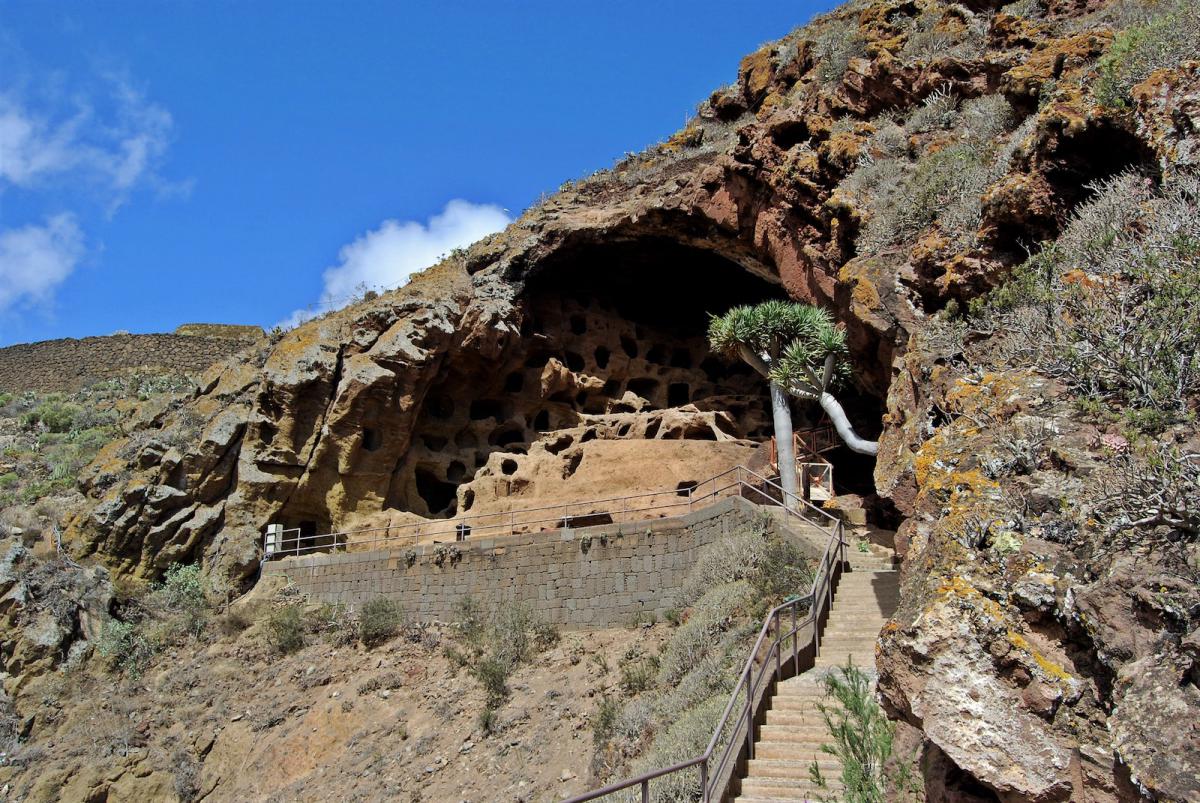 Een lange trap leidt naar een grote spelonk, met daarin een gatenkaas van rotswoningen.