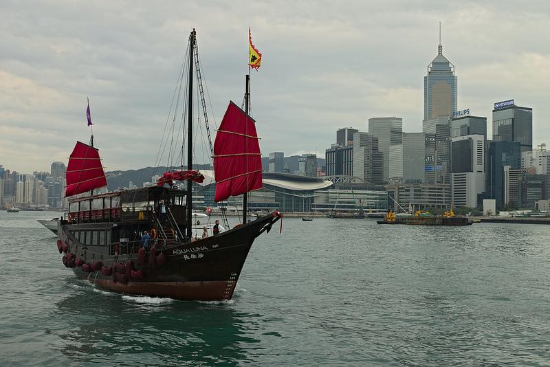(c) Nicolas Vollmer by creative commons Een jonk (Chinese zeilboot) met op de achtergrond de wolkenkrabbers van Hong Kong