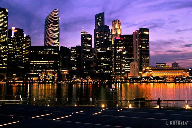 Singapore Night (c) L.Cheryl by Creative Commons Enorme wolkenkrabbers en een paars-oranje horizon.