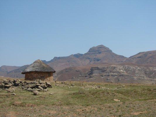 Een traditionele hut met  bergen op de achtergrond.