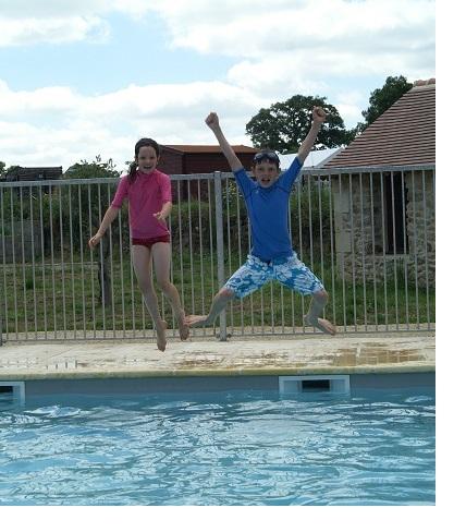 Waterpret aan het zwembad Twee kinderen springen uitgelaten in het water.