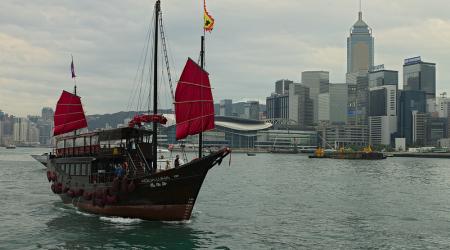 Een jonk (Chinese zeilboot) met op de achtergrond de wolkenkrabbers van Hong Kong