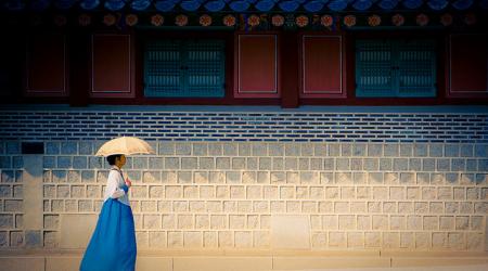 Een poëtische foto uit Seoul, Korea: een vrouw met blauwe jurk en witte parasol wandelt voorbij.