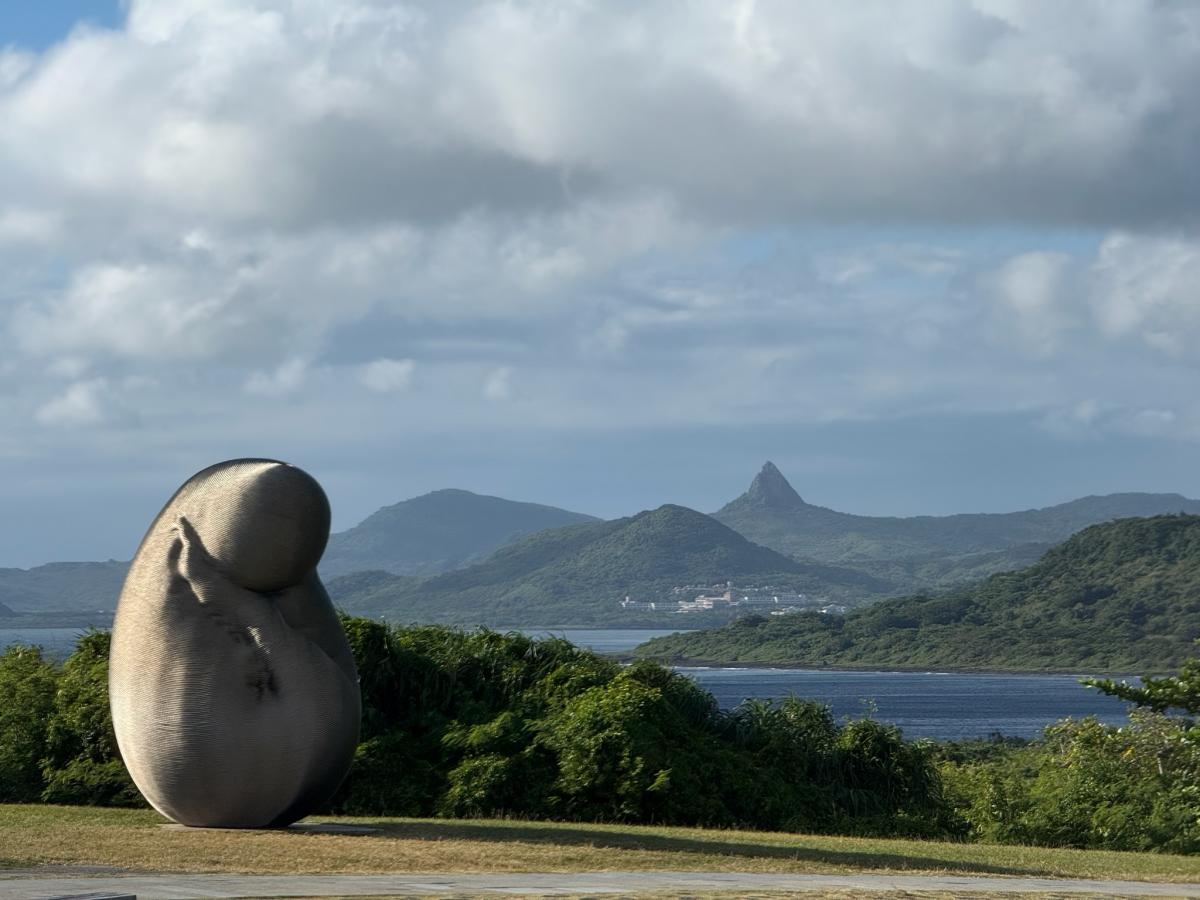 Een modern sculptuur tegen de achtergrond van spitse bergpieken.