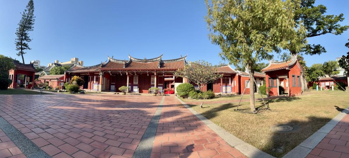 Panoramafoto van de Confuciustempel, met steenrode gebouwen en betegelde paden tussen het groen.
