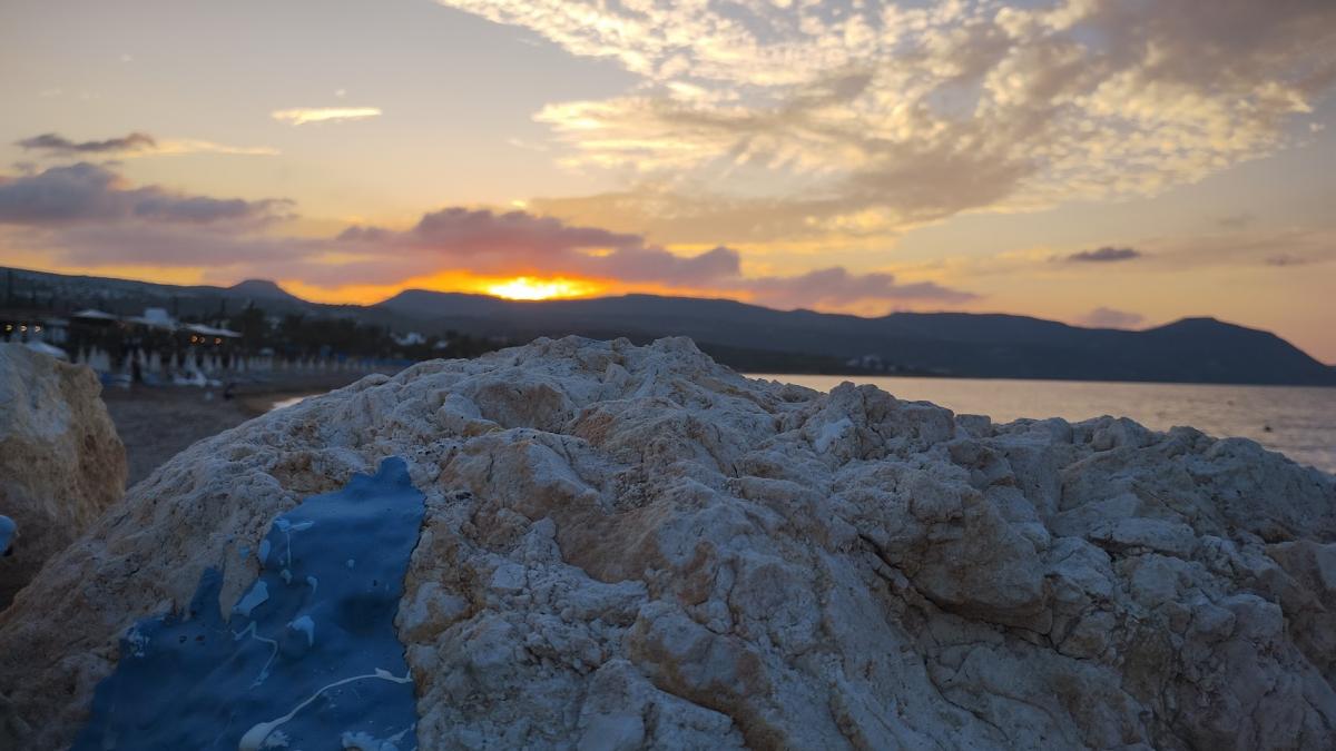 Zonsondergang, gezien van tussen de rotsen aan de kust.