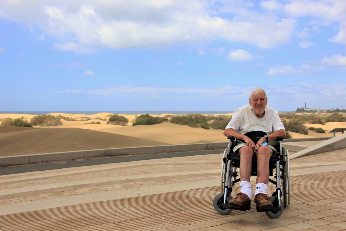 Jozef poseert in zijn rolstoel bij de duinen van Maspalomas.