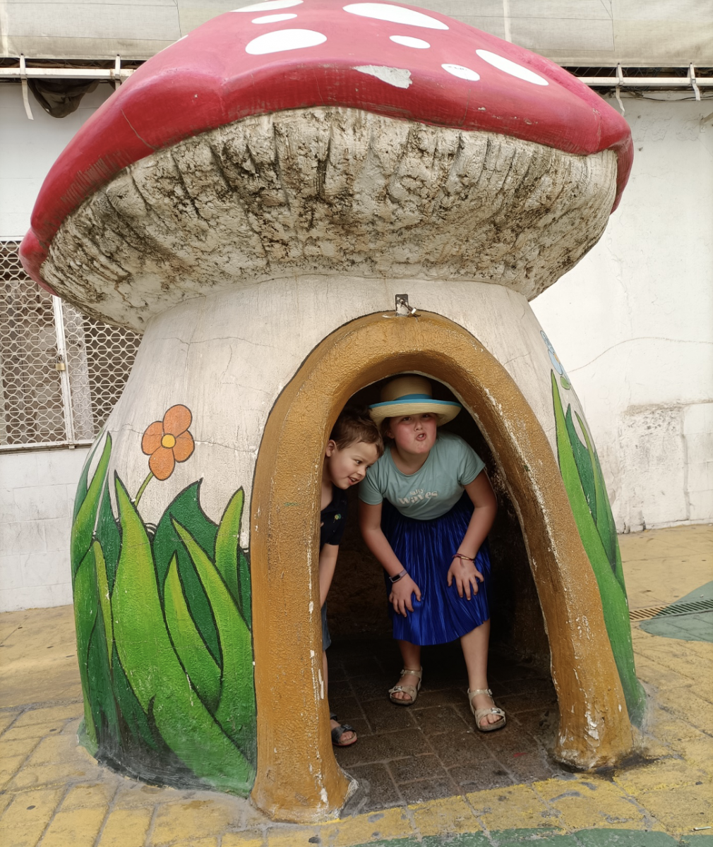 Broer en zus in een "huisje" in de vorm van een paddenstoel. De beschilderde straatstenen kunnen glad zijn.