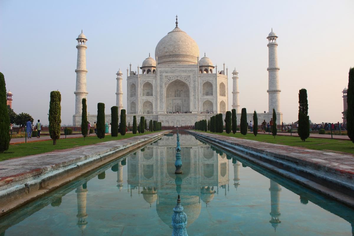 De Taj Mahal in het vroege ochtendlicht, weerspiegeld in de vijver ervoor.