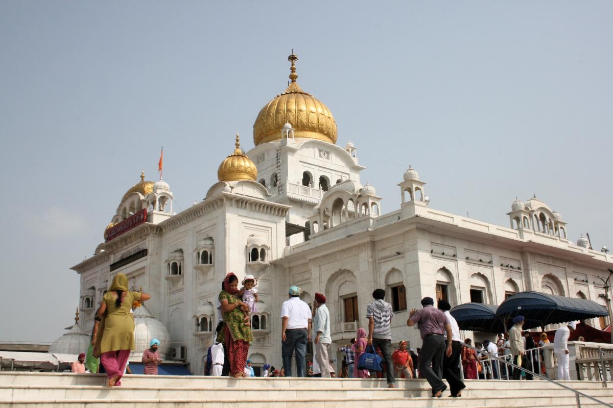 Witte tempel met gouden daken. In de omgeving herkennen we sikhs met hun typische tulband.