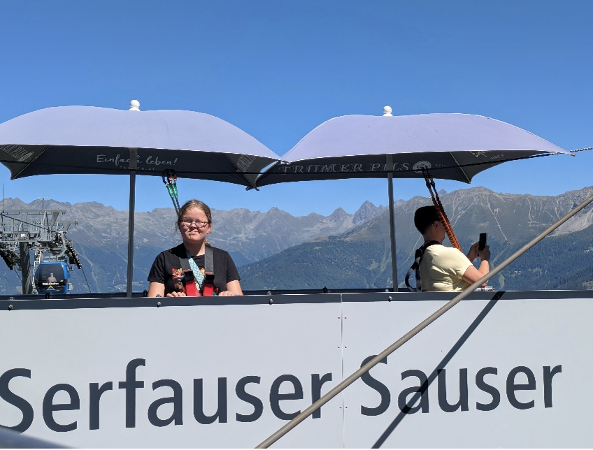 Onder een staalblauwe hemel en parasols met opschrift "Einfach Leben" (gewoon leven) wacht grote zus op haar beurt.
