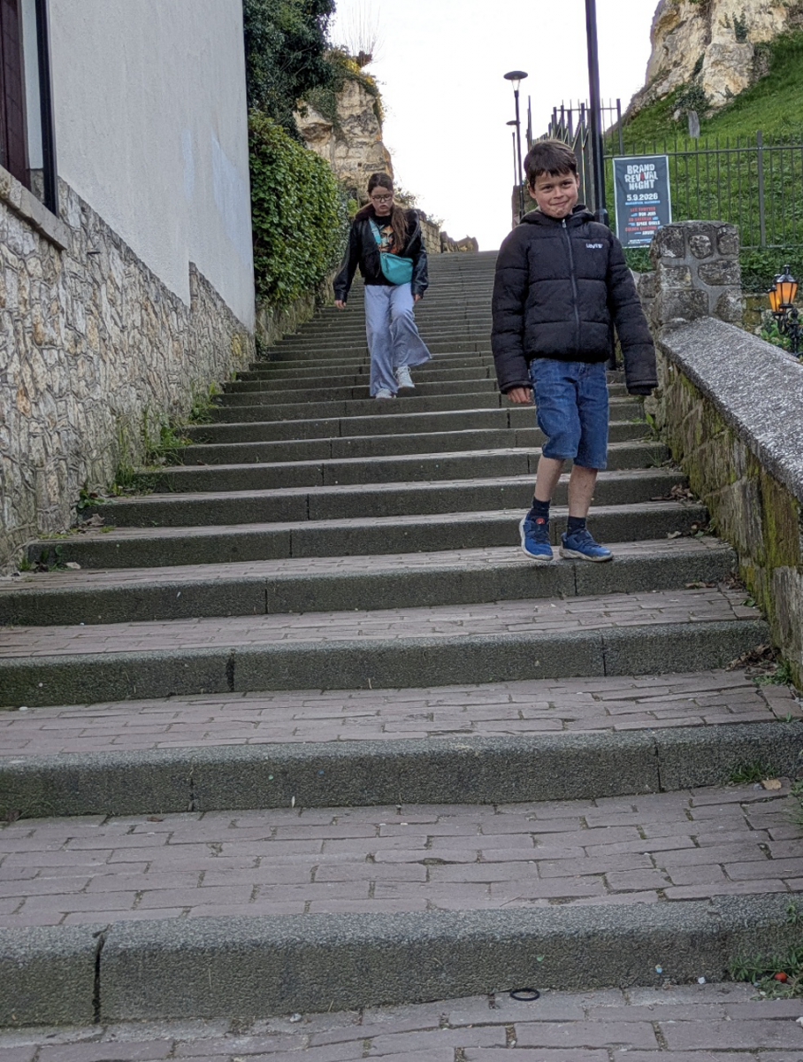 We kijken op naar de kinderen die een hoge stenen trap afdalen.